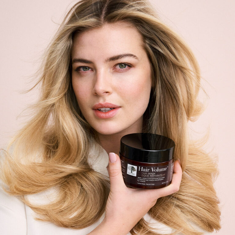 Model with voluminous hair holding New Nordic Hair Volume™ Repair Mask.