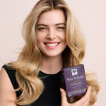 Smiling woman with long, voluminous blonde hair holding the Hair Volume™ package.