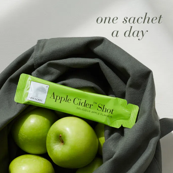 A single Apple Cider™ Shot sachet displayed in a bag with apples with text One sachet a day.
