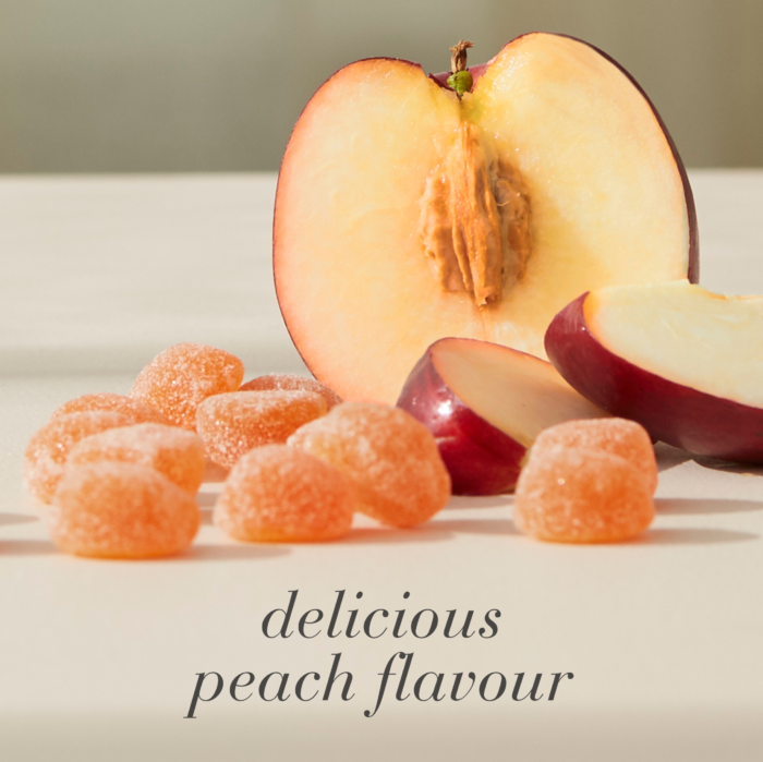 Peach gummies displayed beside sliced peach fruit, highlighting a delicious peach-flavoured gummy supplement.