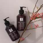 New Nordic Hair Volume™ shampoo and conditioner bottles shown with flowering branches, highlighting a natural hair care routine.