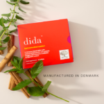 The red Dida™ package surrounded by cinnamon sticks and natural herbs with text Manufactured in Denmark.