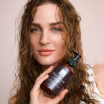 Beautiful woman with wet hair holding the Hair Volume™ Conditioner, representing healthy shine and strength.