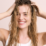 Beautiful woman with wet hair smiling, showcasing natural shine and healthy-looking strength.