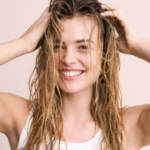 Beautiful woman with wet hair smiling, showcasing natural shine and healthy-looking strength.