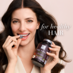 Beautiful woman with strong, dark hair holding the Hair Volume™ Gummies bucket and biting into a single gummy.