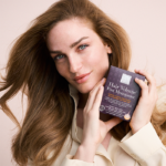 Woman with beautiful red, thick hair holding the dark purple Hair Volume™ Post Menopause package.