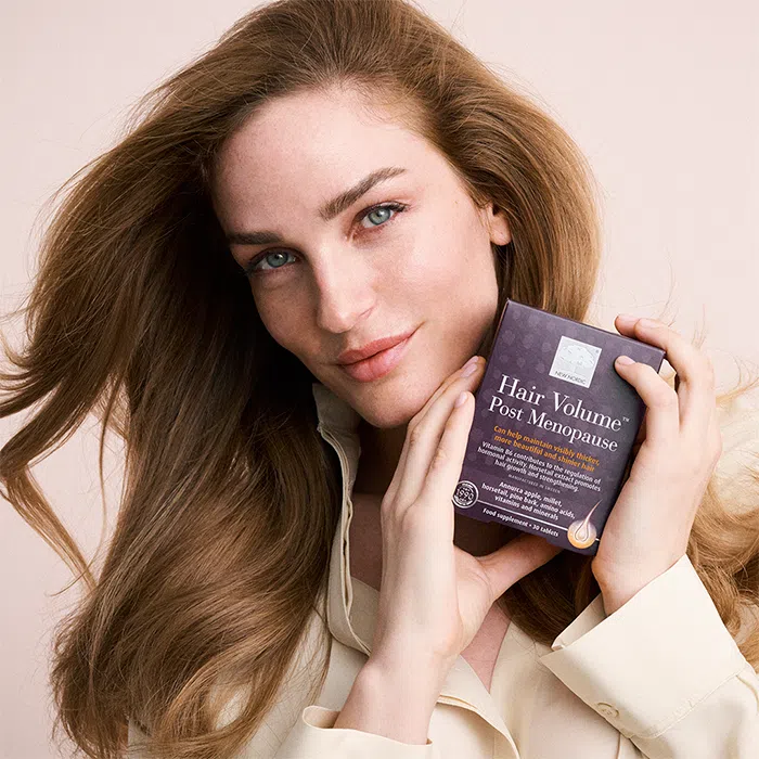 Woman with beautiful red, thick hair holding the dark purple Hair Volume™ Post Menopause package.