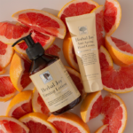Herbal Joy™ Firming Lotion and Herbal Joy™ Anti-Ageing Hand Cream resting on freshly cut grapefruit.