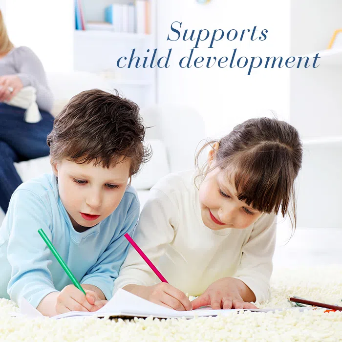 Children laying on a carpet while drawing with text Supporting healthy child development.