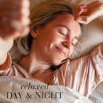 Woman resting in bed with eyes closed and smiling, conveying relaxation and a calm day-and-night routine.