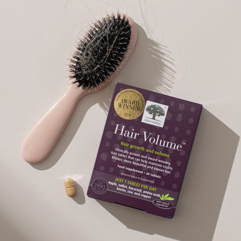 New Nordic Hair Volume™ supplement for hair growth, shown with tablet and hairbrush