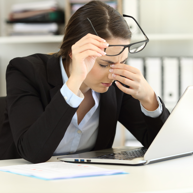 Tired woman sitting by her computer, feeling fatigued and stressed