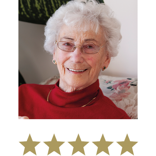 Wonder Legs⢠8 Image of a older woman smiling wearing glasses sat on her sofa with five stars beneath.