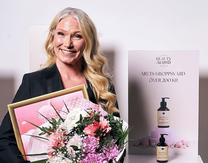 Woman holding a bouquet of flowers and an award, smiling in a celebratory moment.
