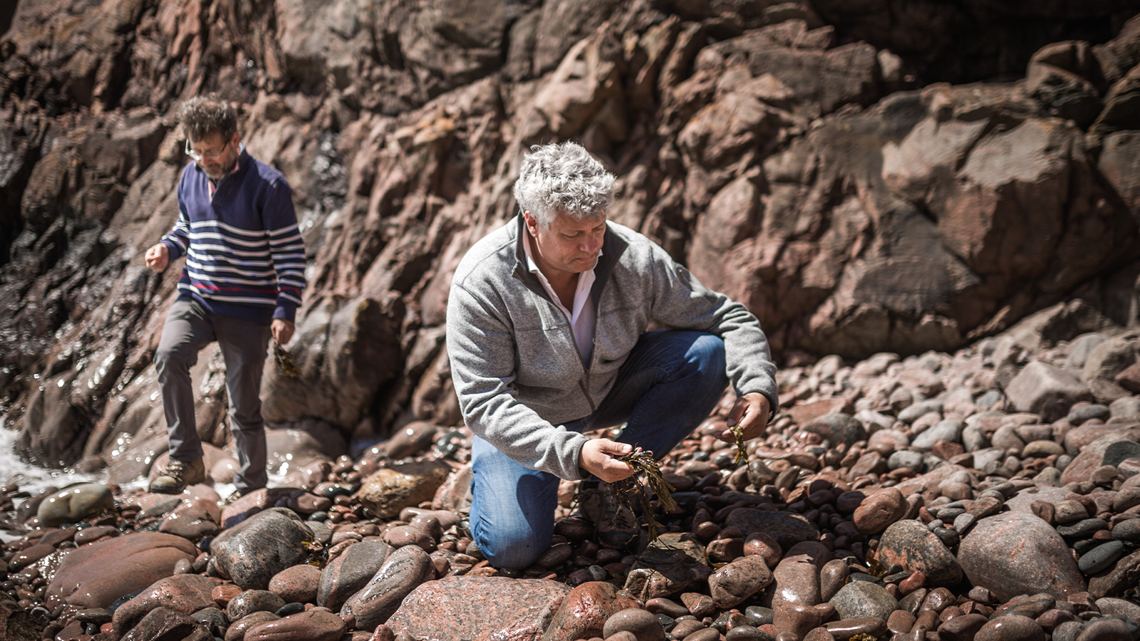 Two men exploring nature, surrounded by rocky cliffs.