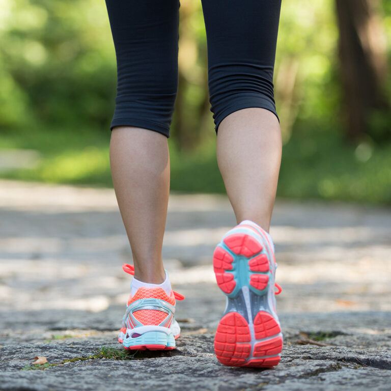 Back of woman’s legs wearing running shoes.