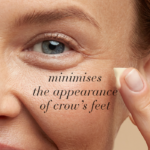 Woman applying eye cream with text Minimises the appearance of crow’s feet.