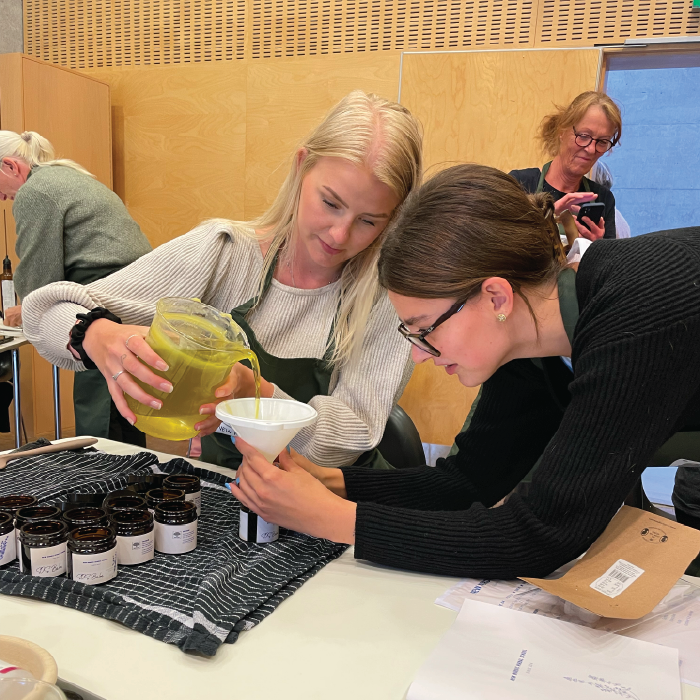 Herbal Schools 34 Two women experimenting with herbs at a herbal school event, learning about and engaging with plants.