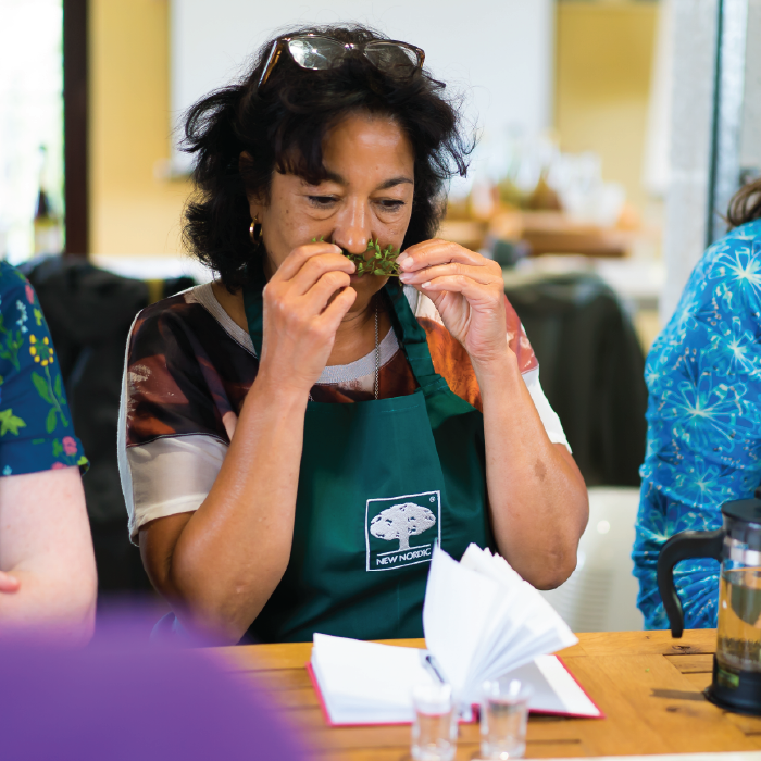 Herbal Schools 36 Woman smelling herbs at a herbal school event, engaging with plants and learning about their uses.