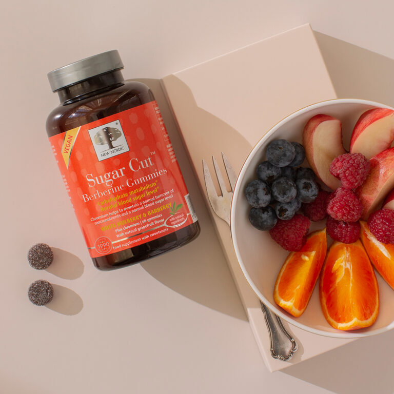 a glass of sugar cut berberine gummies next to a bowl on fruits