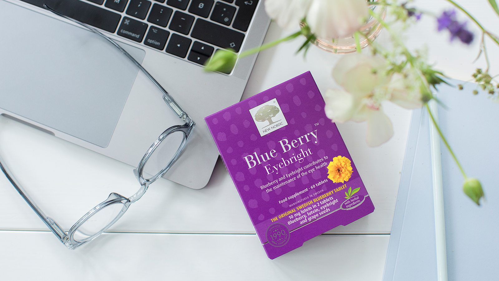 Blue Berry™ Eyebright Plus 18 A pack og Blue Berry tablets on a table with a laptop and a pair of classes