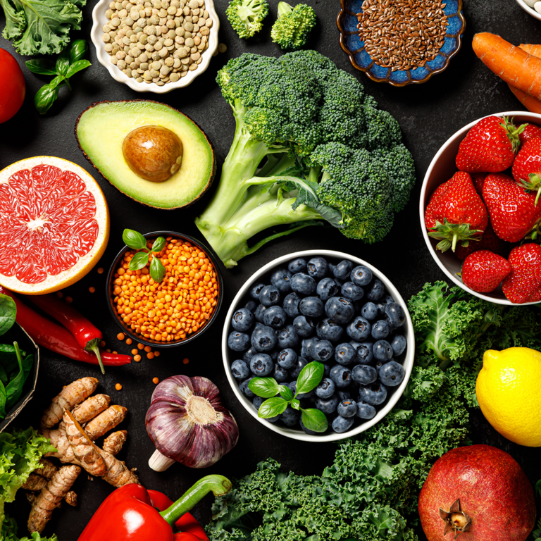 A colorful selection of nutritious foods, including broccoli, avocado, and blueberries arranged together.