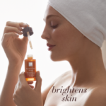 Woman with towel-wrapped hair applying Pigment Clear Serum with dropper, highlighting skin-brightening benefits.