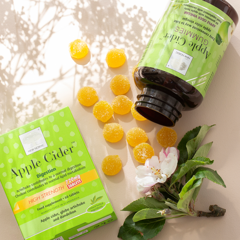 Pack of apple cider high strength tablets and apple cider gummies with the gummies pouring out and an apple flower