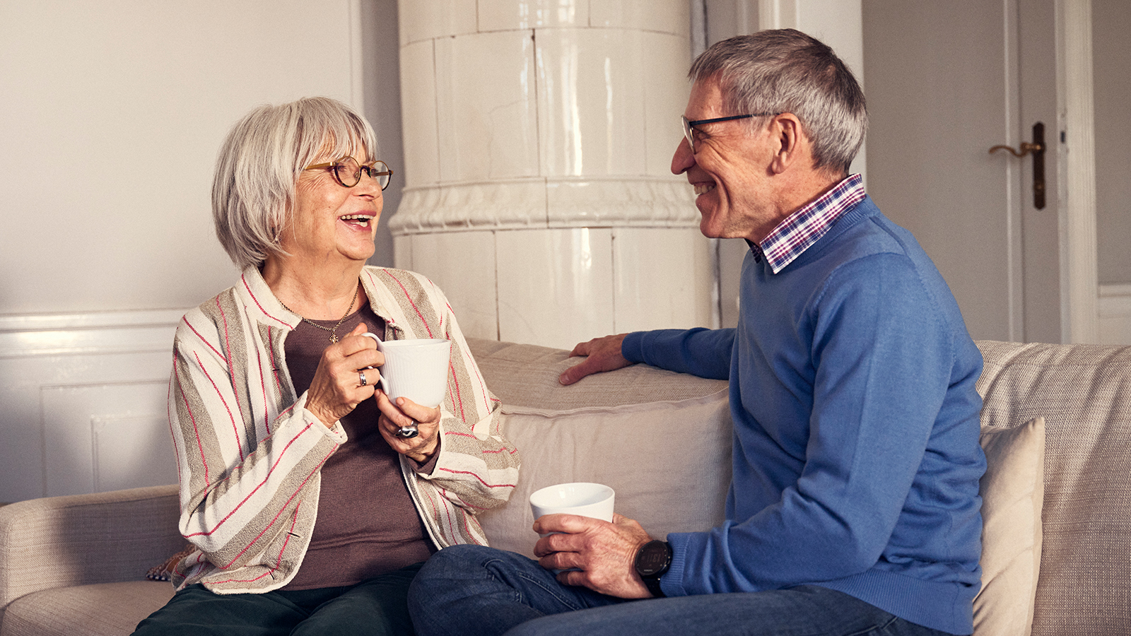 Man and woman say on a sofa with a cup of tea and smiling
