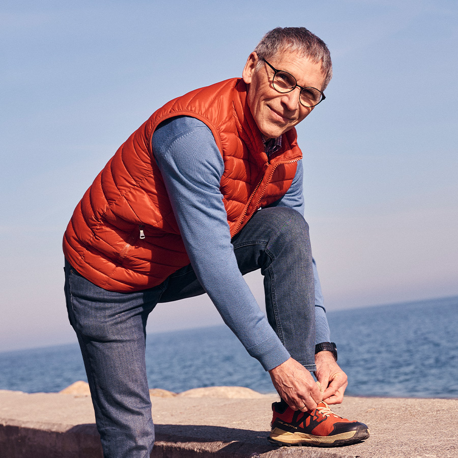 Smiling man tying his shoelaces up with the sea in the background