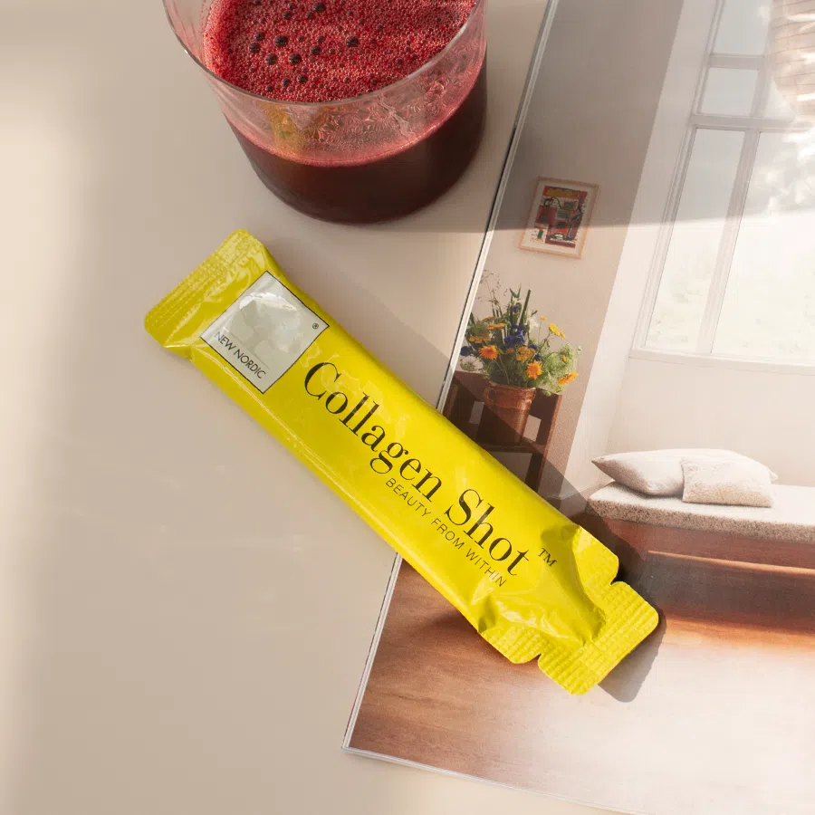 Collagen Shot sachet on an open magazine and beside a smoothie