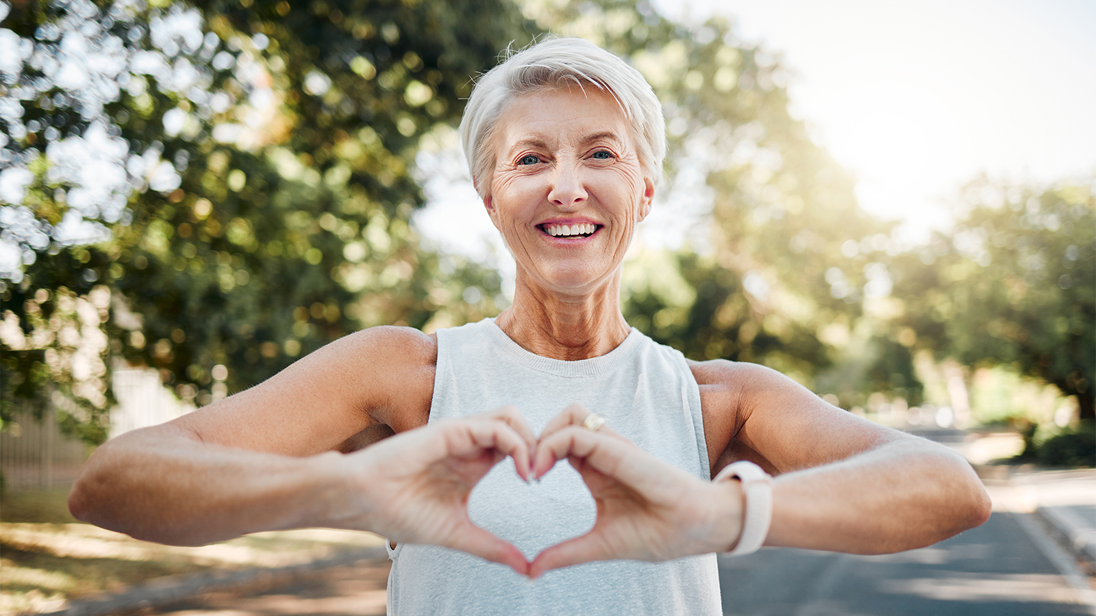 Woman smiling and making a heart with her hands infront of her