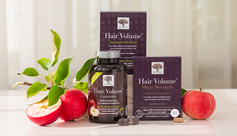 New Nordic Hair Volume™ supplements in tablets and gummies, displayed with fresh apples.