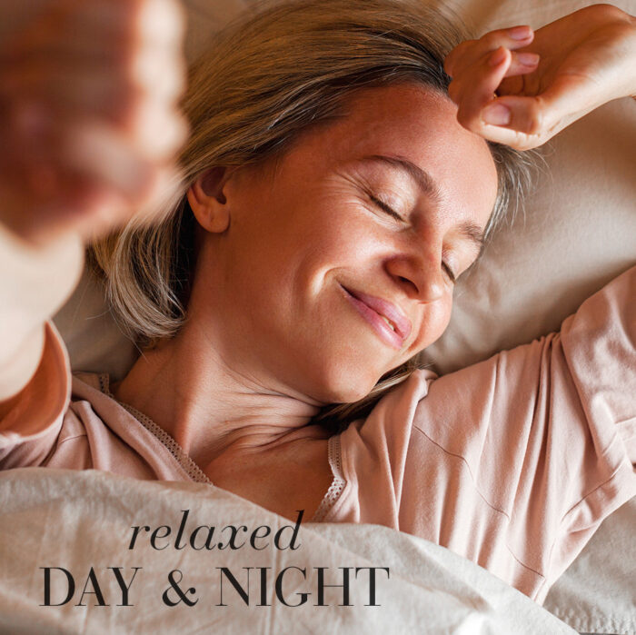 Woman relaxing in bed with her eyes closed and a smile, with the text “relaxed day & night.”